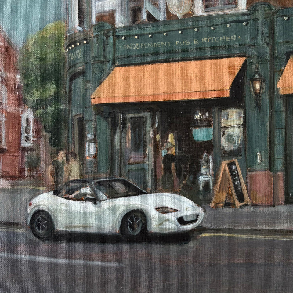 Original oil painting of the Independent Pub & Kitchen by Minuca Sostres, a corner building with dark green frontage, orange awnings and a white convertible passing by.
