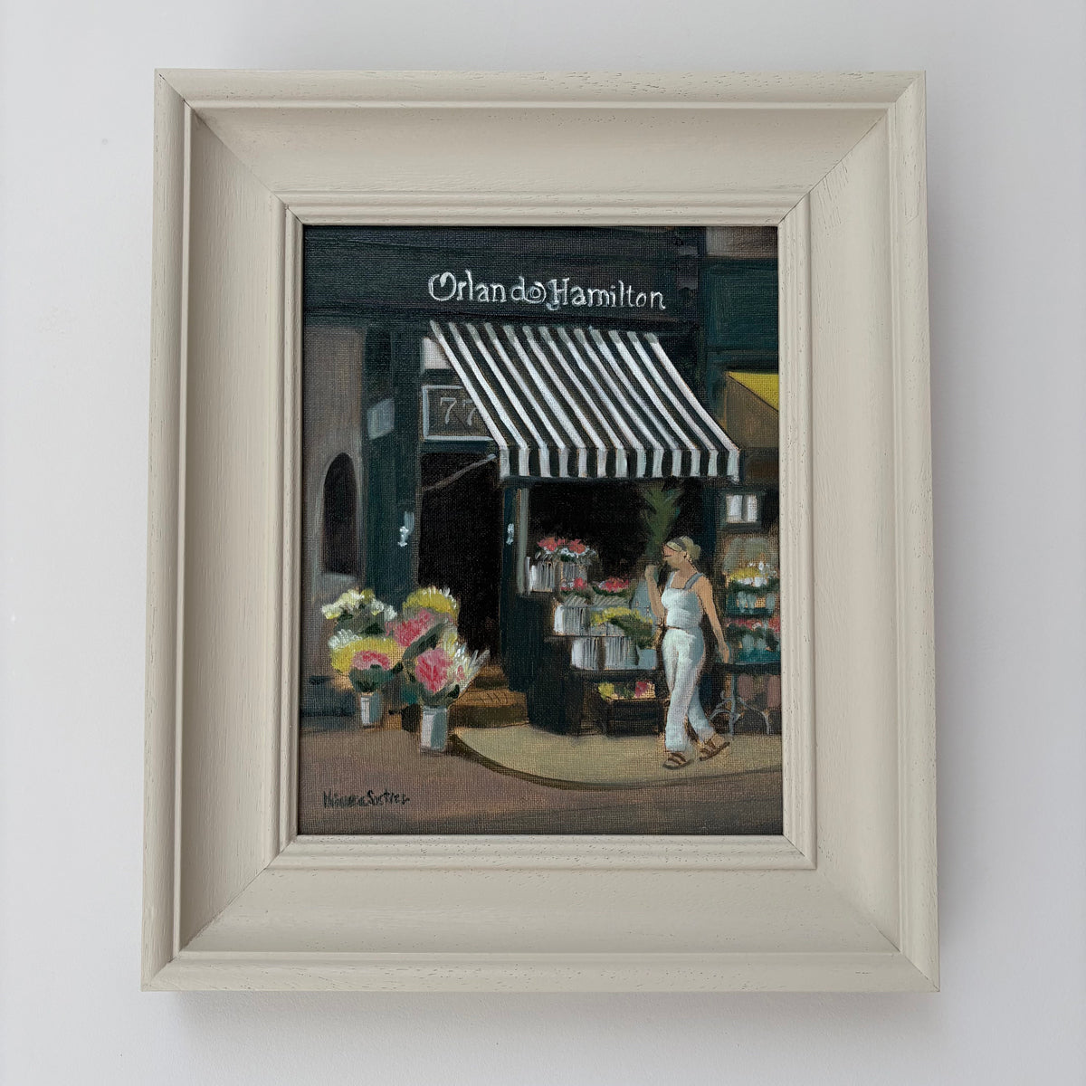 Framed oil painting of Orlando Hamilton flower shop by Minuca Sostres, showing bouquets beneath a striped awning and a woman walking past.