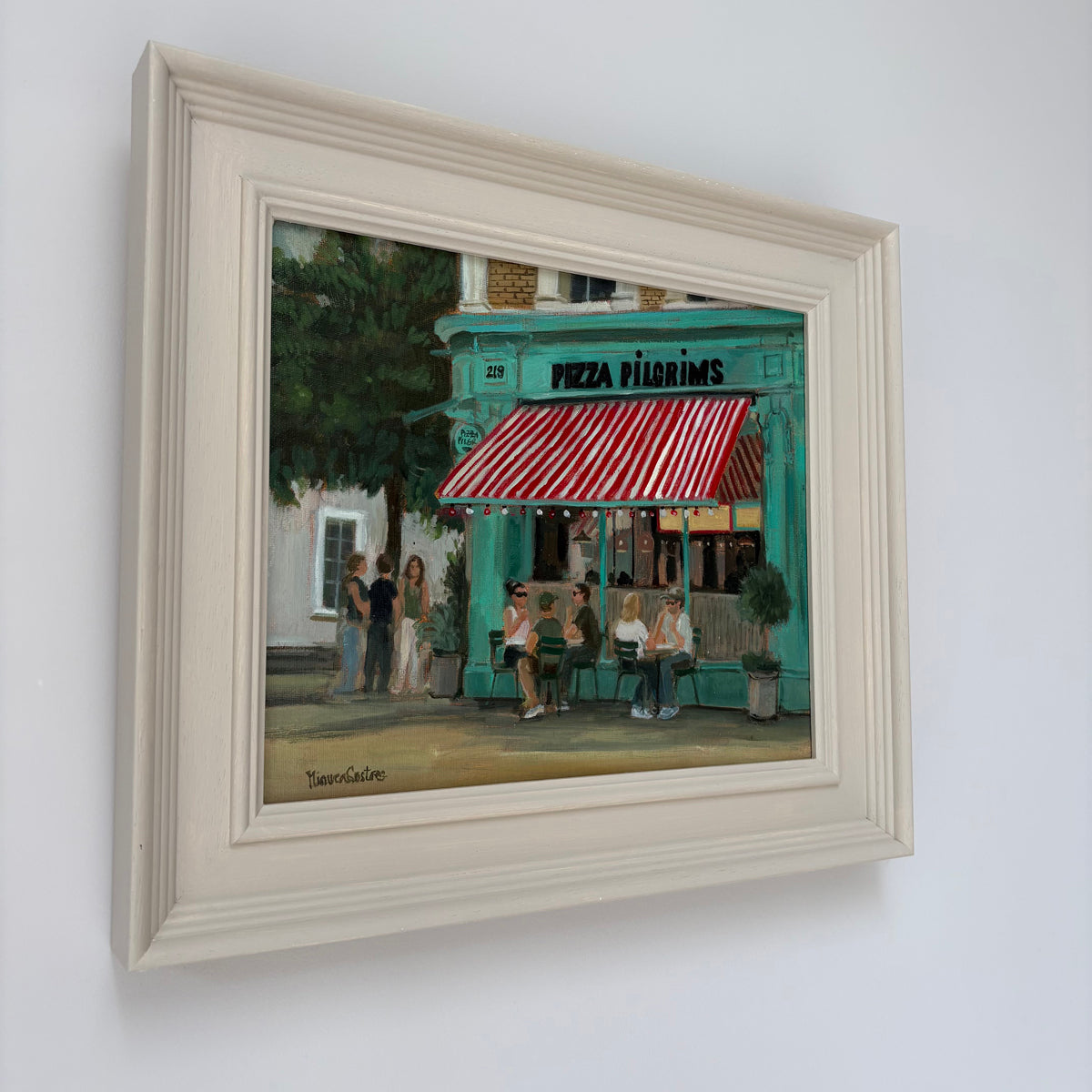 Framed oil painting of Pizza Pilgrims by Minuca Sostres, showing its turquoise storefront, red-and-white striped awning and people seated outside.